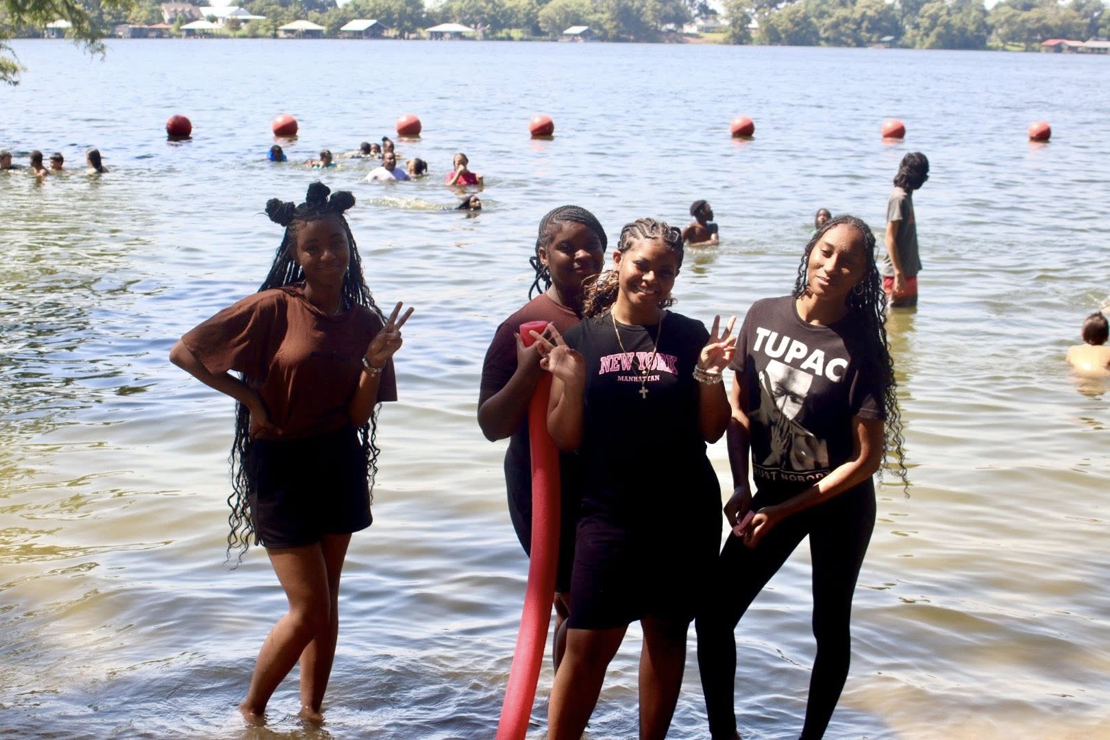 Four girls posing for a picture by a lake.